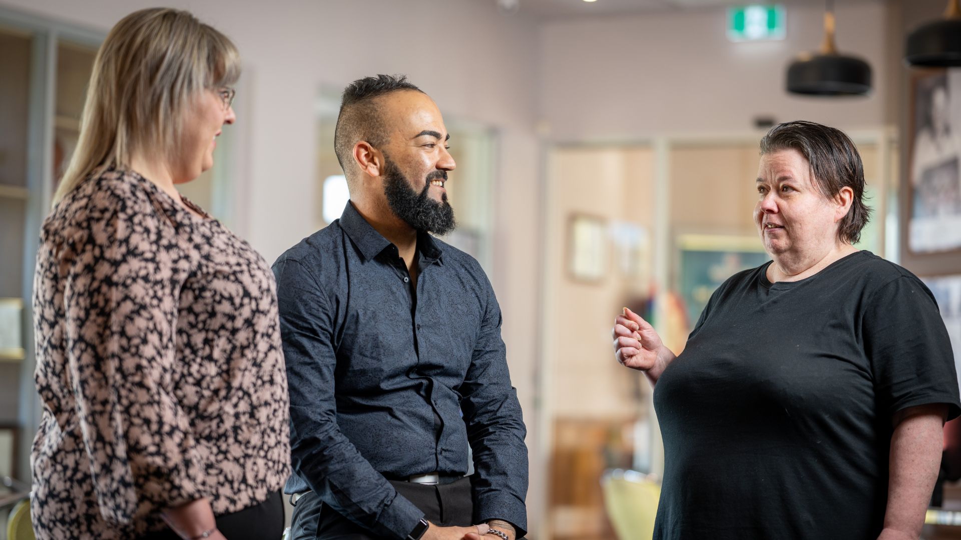 Three people including a worker of inclusive employment talk in a community venue